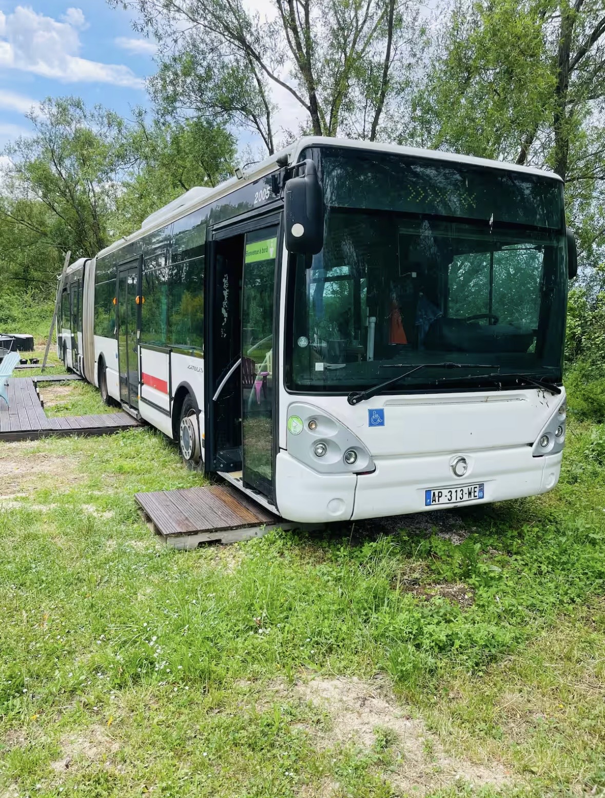 Le Bus Insolite en plein jour — façade colorée entourée de verdure