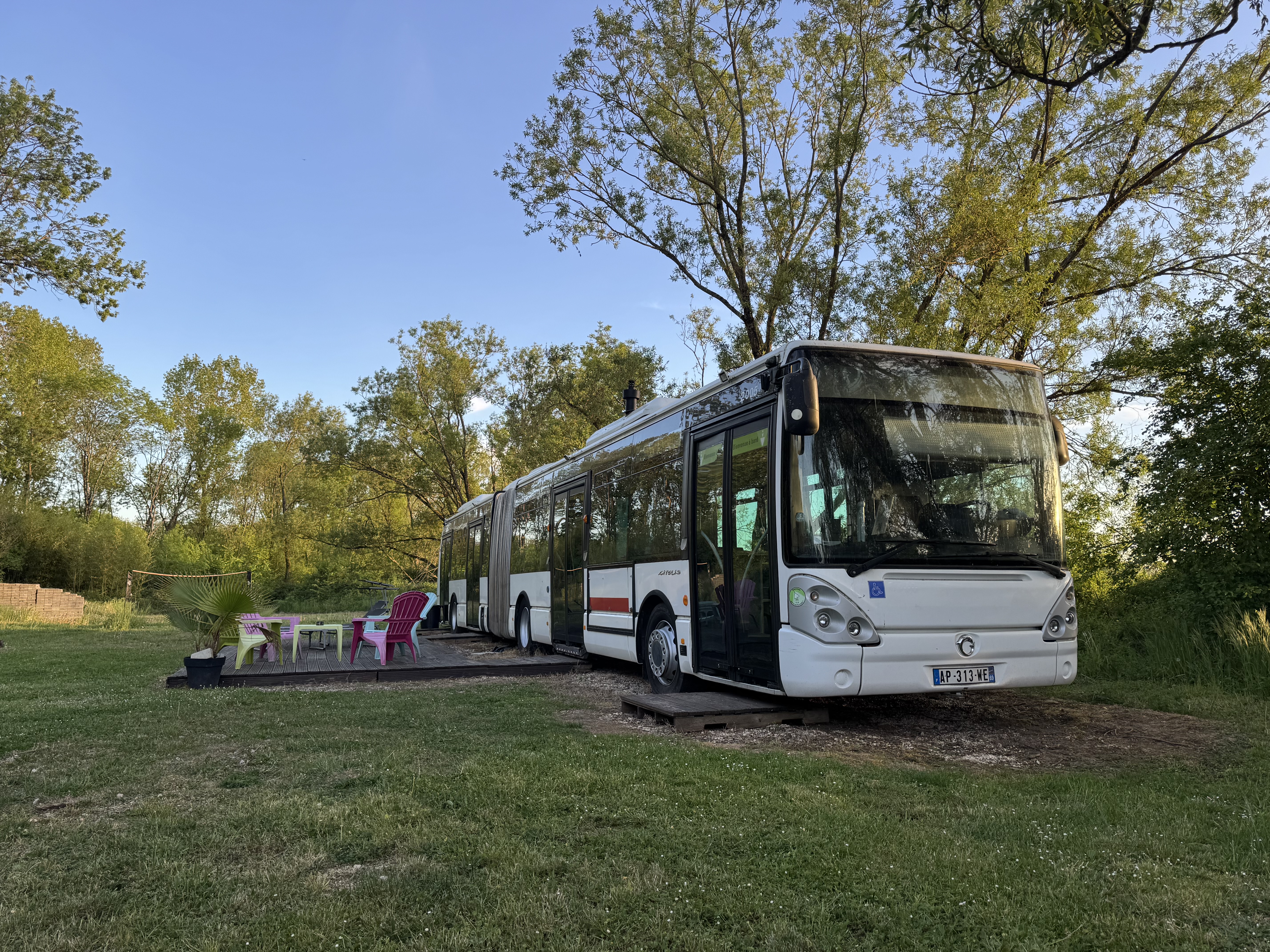 Le Bus Insolite en plein jour — façade colorée entourée de verdure